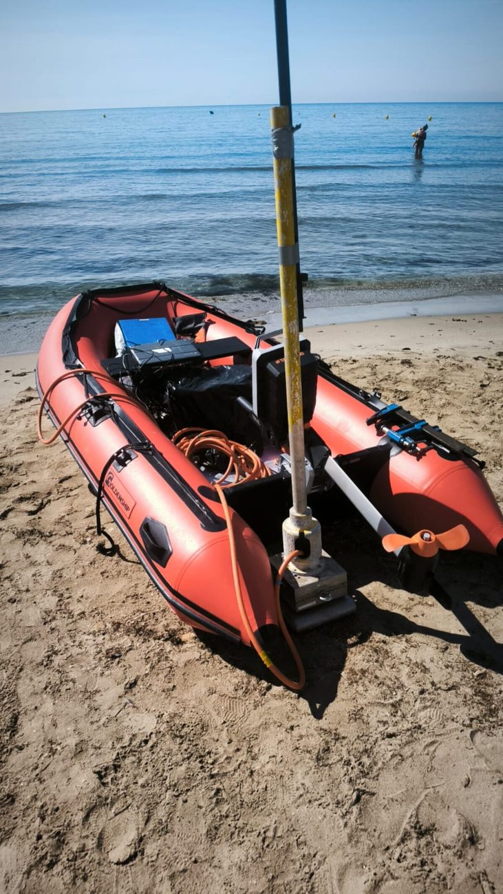 Embarcació amfíbia amb pal de tomografia elèctrica a la platja, amb un submarinista al mar de fons
